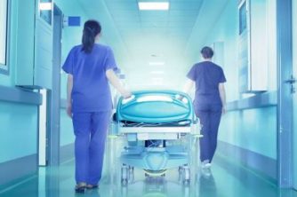 Two nurses pushing a hospital bed