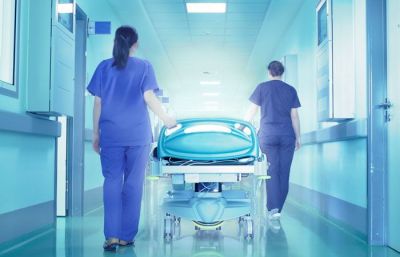 Two nurses pushing a hospital bed