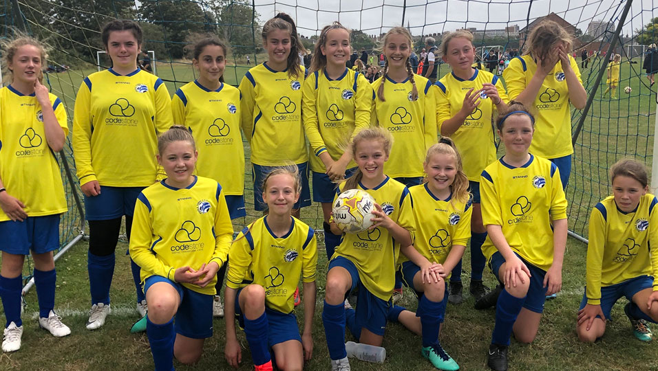 A girl's football team wearing yellow Codestone shirts.